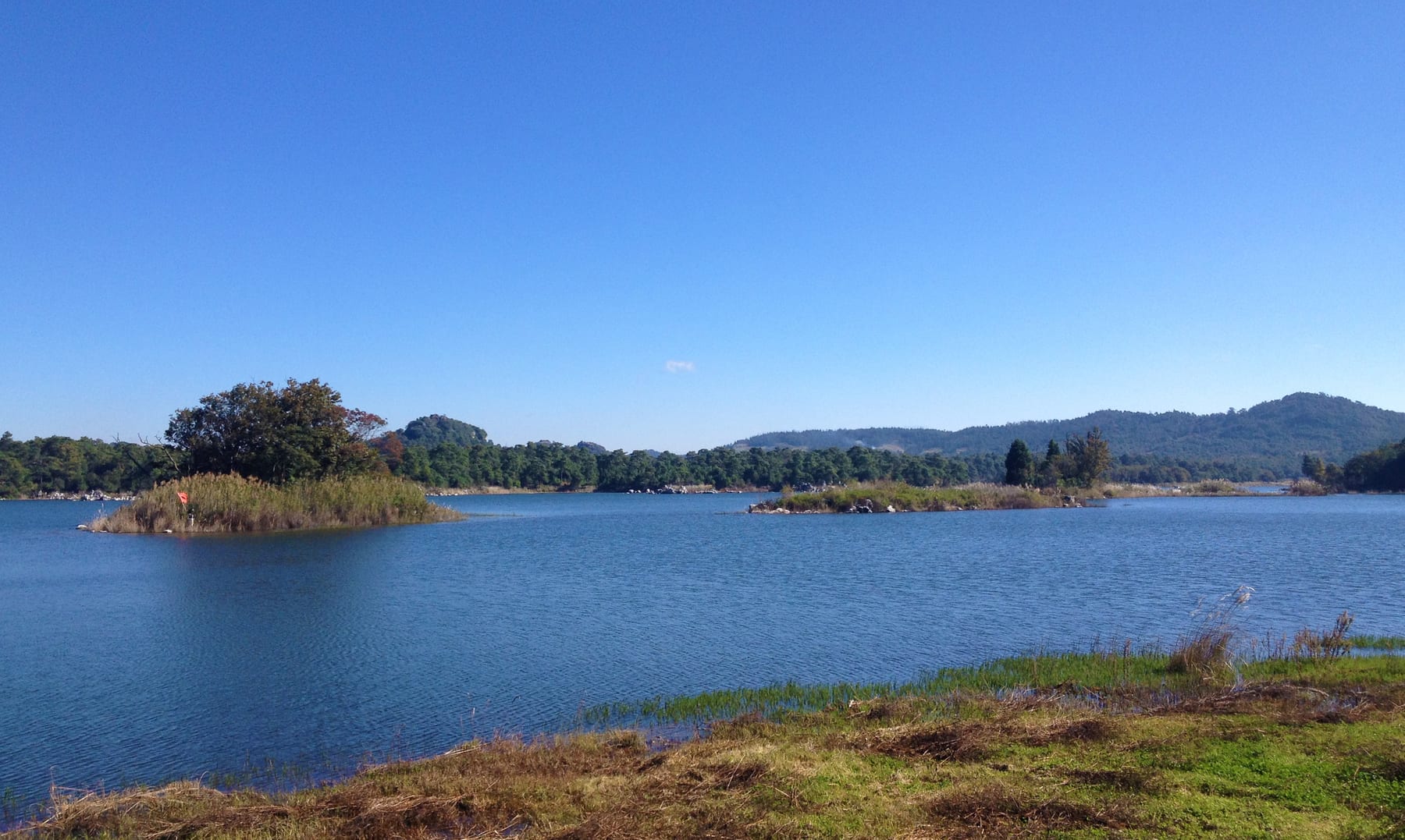 Changhu, the Long Lake in Shilin county, with small wooded islets and a grassy shore