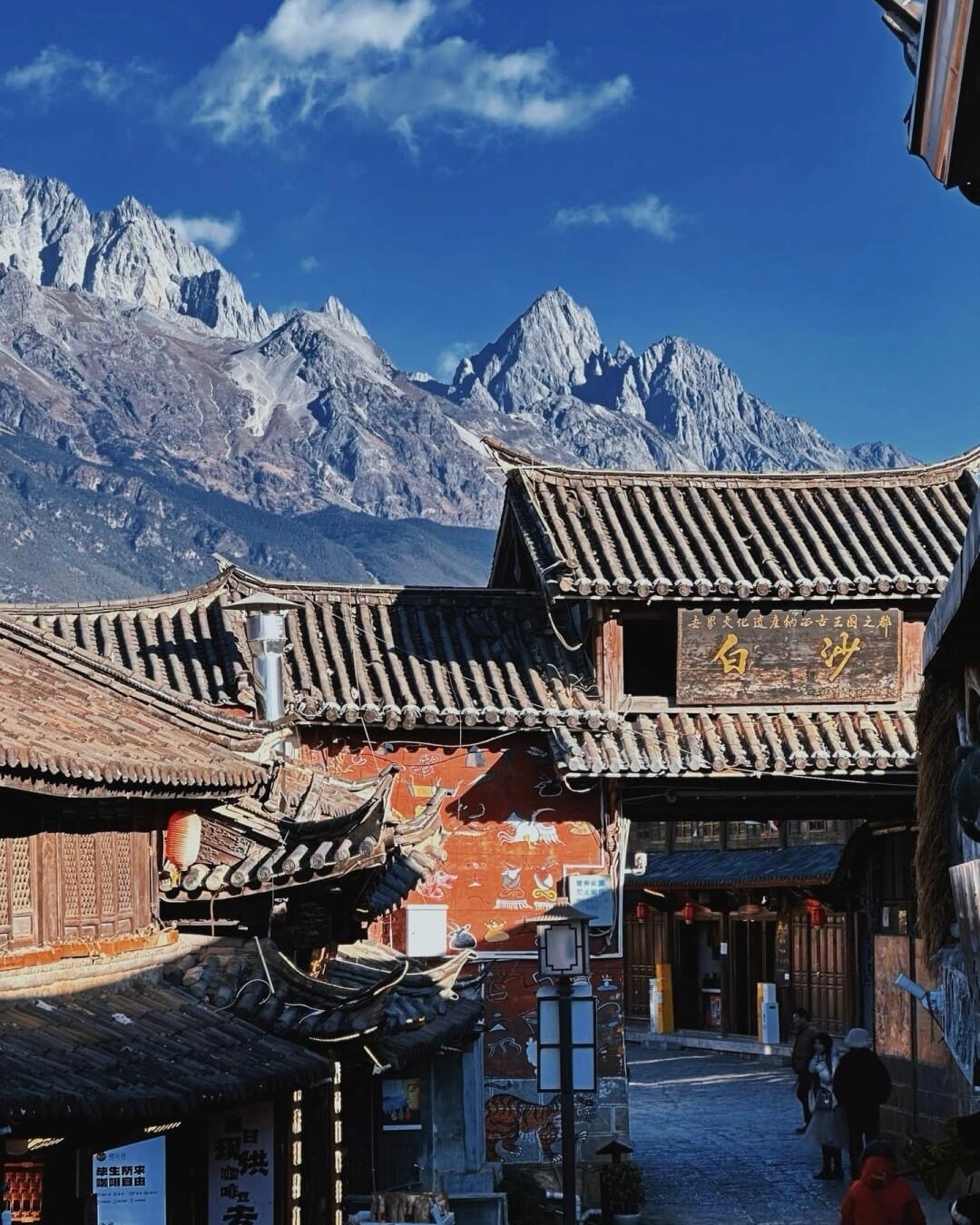 The Baisha old-town gate and painted mural wall with Jade Dragon Snow Mountain behind