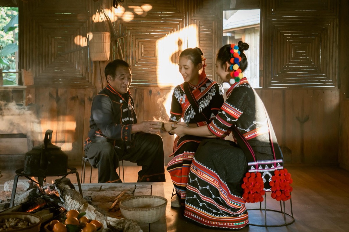 Fireside roasted-tea welcome in a traditional village home — the Bulang hearth ritual, Yunnan