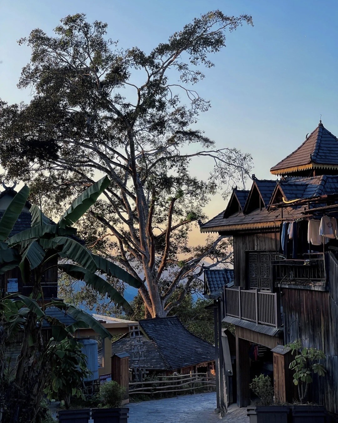 Wooden Dai stilt houses with tiered tiled roofs at dusk, Xishuangbanna, southern Yunnan