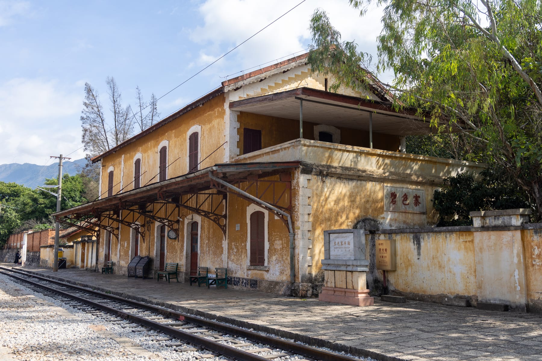 Bisezhai station in Mengzi — the yellow French station building with louvred shutters and its platform canopy