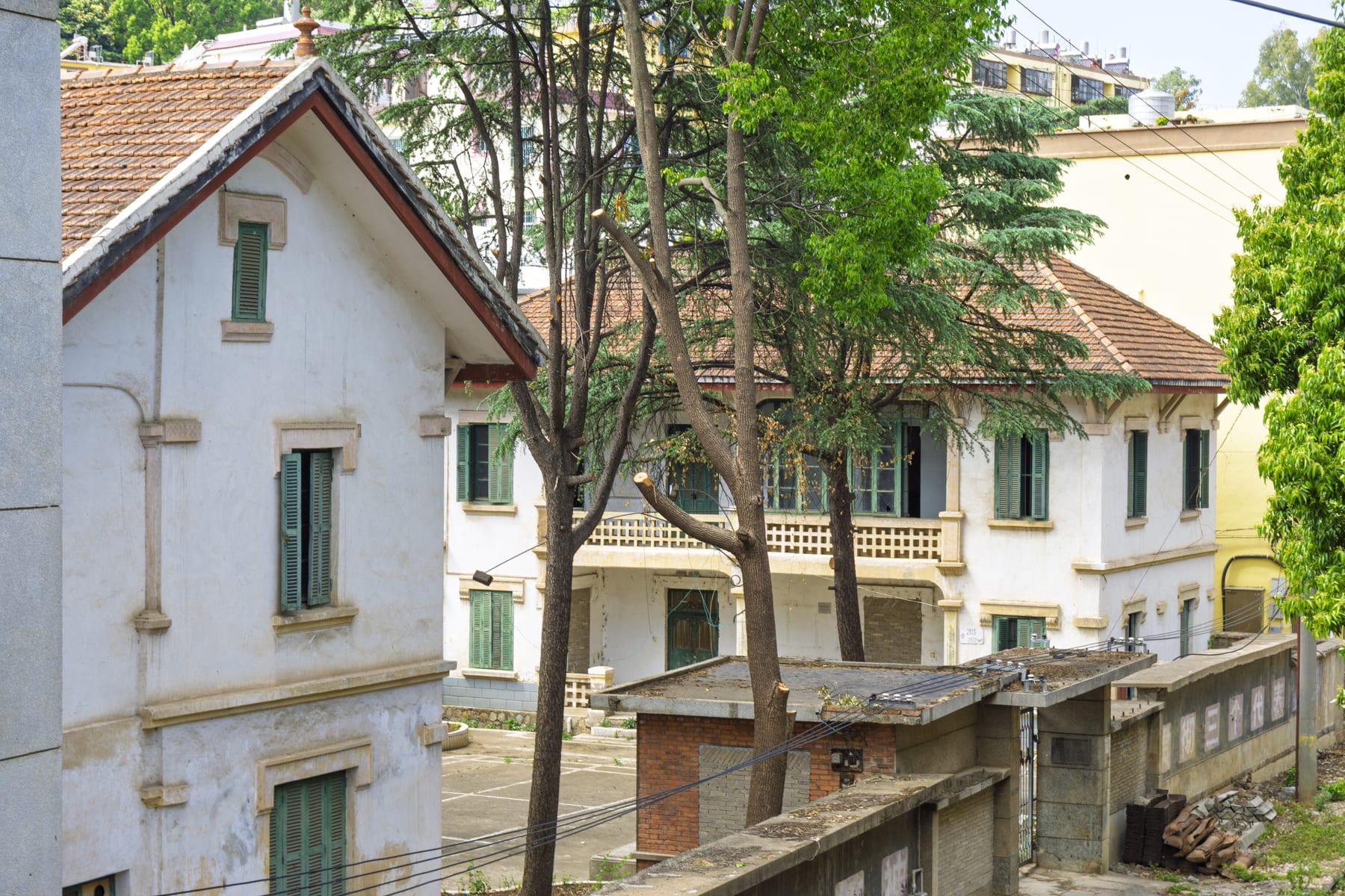 French-era railway buildings at Yiliang station, with tiled roofs, green shutters and a balustraded balcony