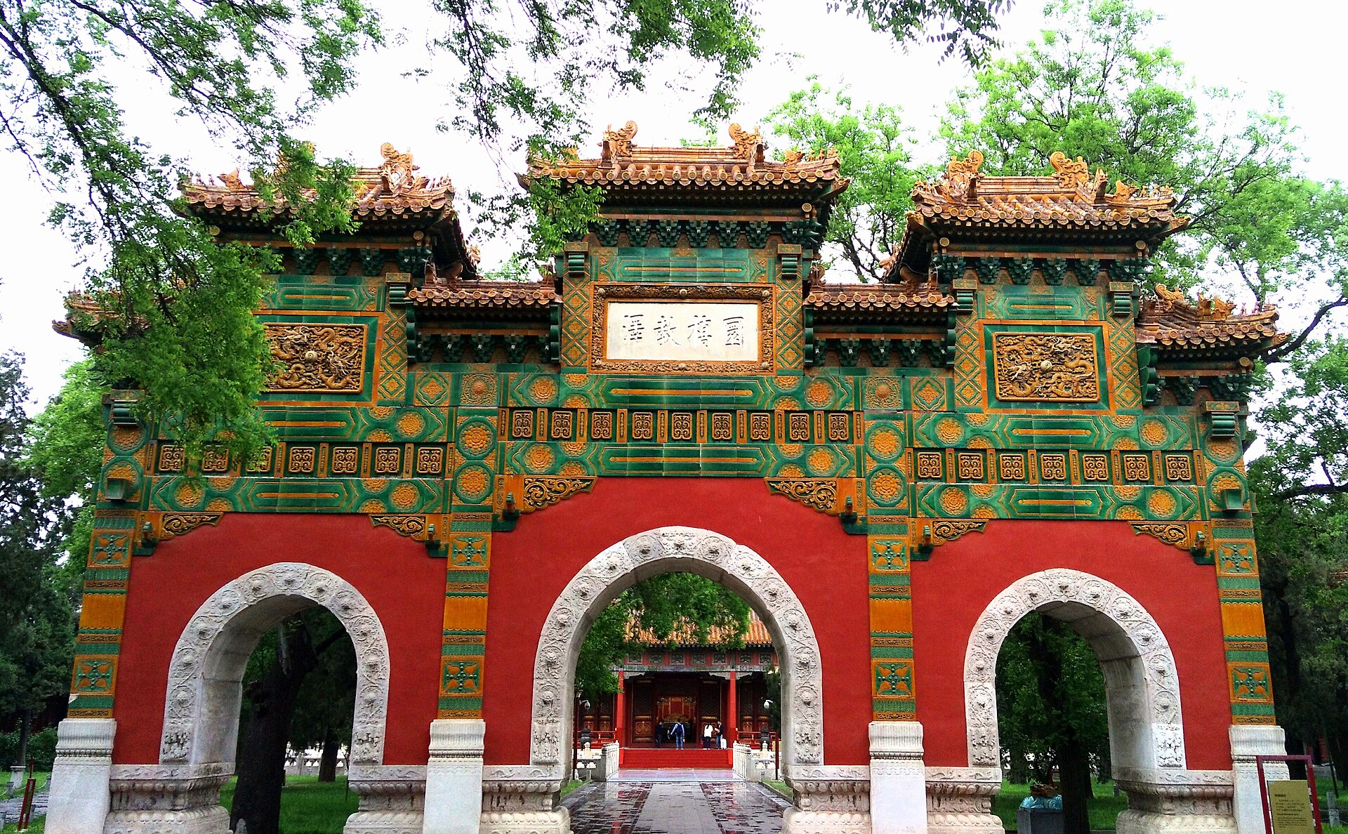 The glazed green-and-gold triple archway (琉璃牌坊) of the Guozijian Imperial College, a hall framed through the central arch, Beijing