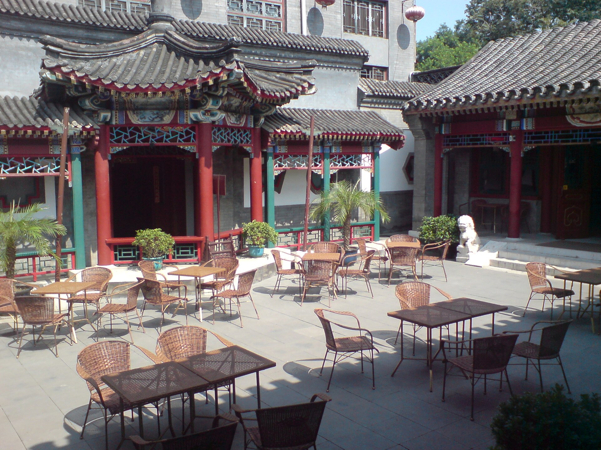 A traditional siheyuan courtyard (四合院) with red lacquer columns, upturned grey eaves and red lanterns, Beijing