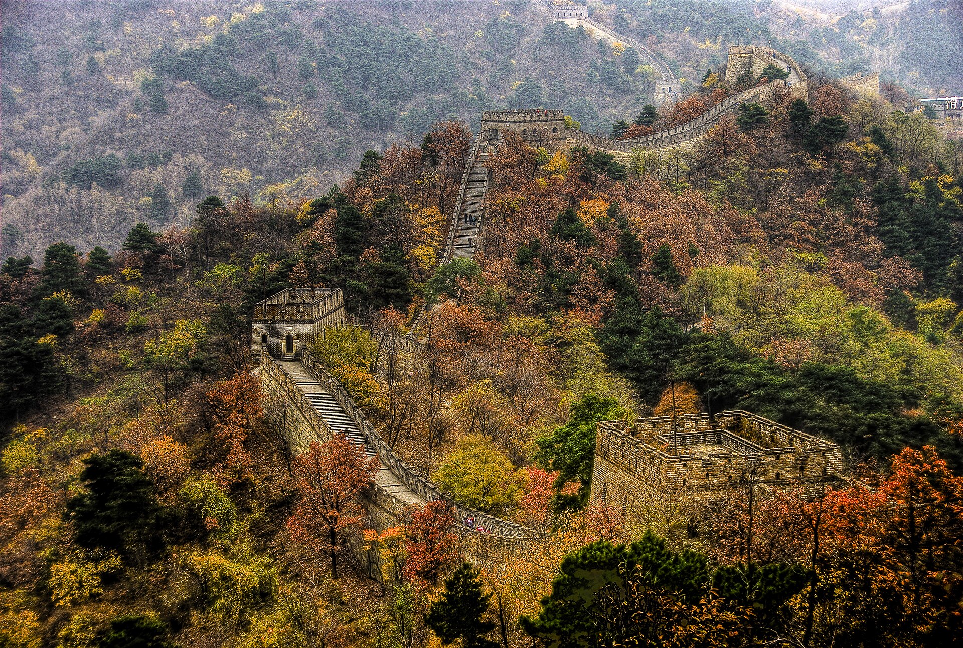 The Great Wall at Mutianyu (慕田峪长城) winding across forested ridges ablaze with autumn colour, its watchtowers stepping into the hills, Beijing
