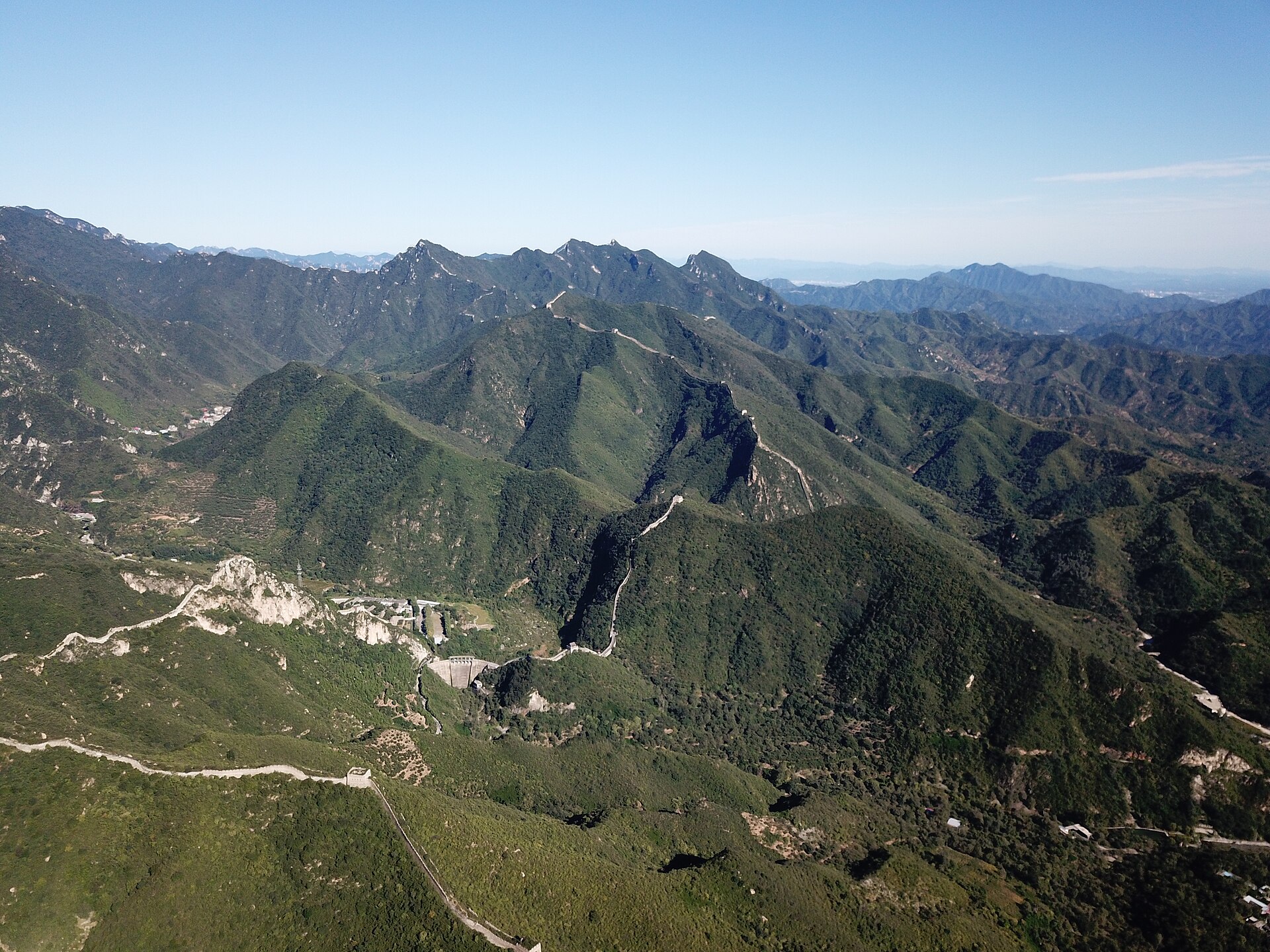 The restored Great Wall at Mutianyu (慕田峪) snaking along a forested ridgeline, watchtowers strung out toward the horizon — quieter than Badaling, Beijing