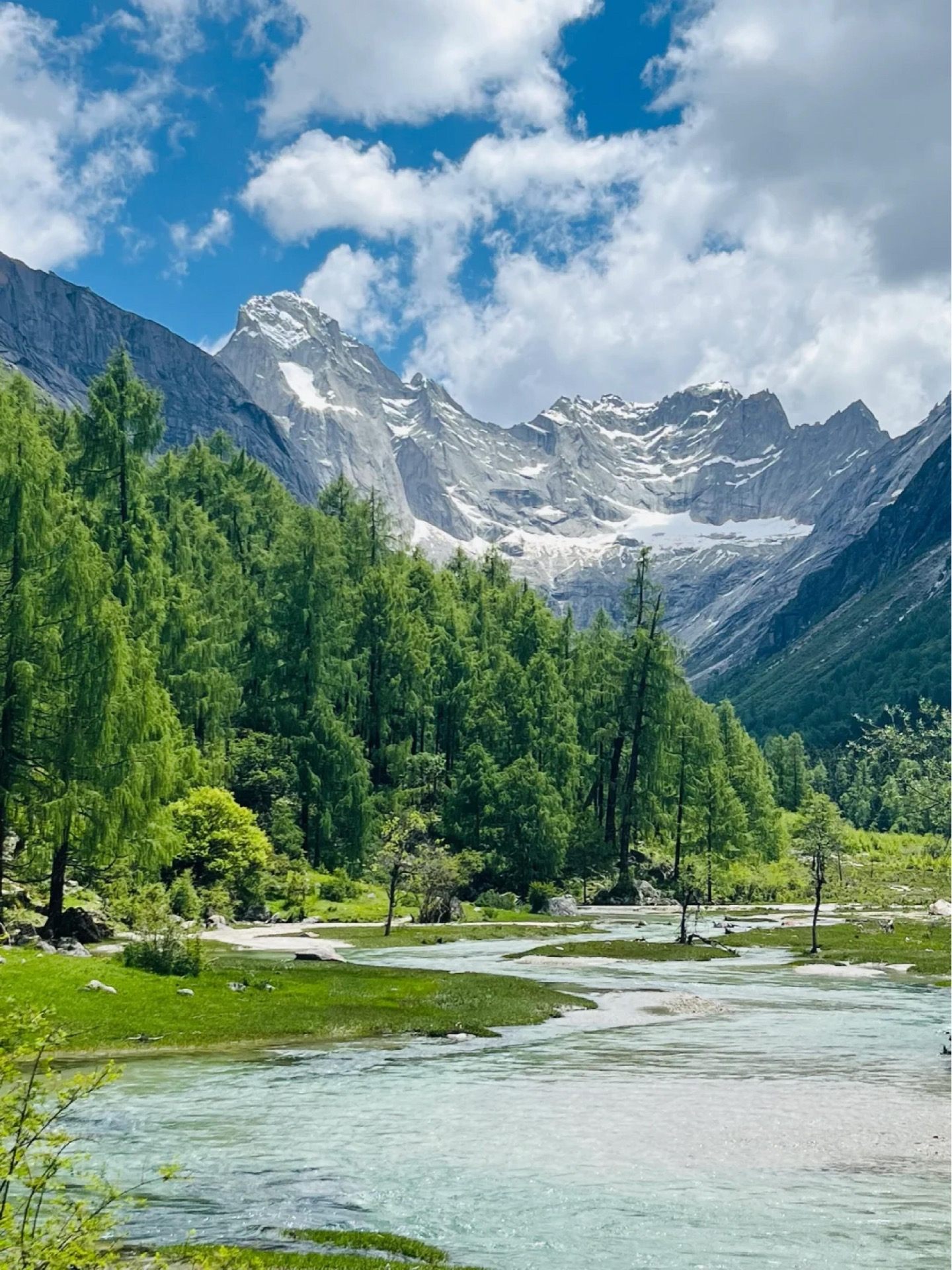 Four-sisters peaks of Siguniang rising over a turquoise river at Rilong