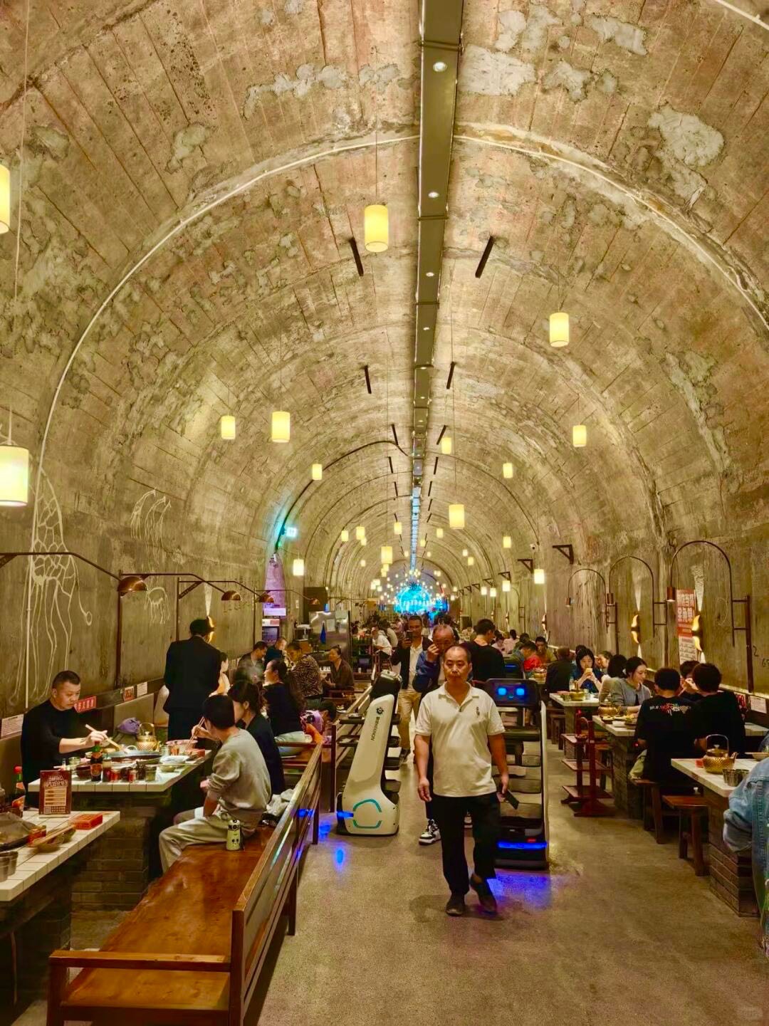 Diners fill long tables inside a vaulted former air-raid tunnel converted into a hotpot restaurant in Chongqing.