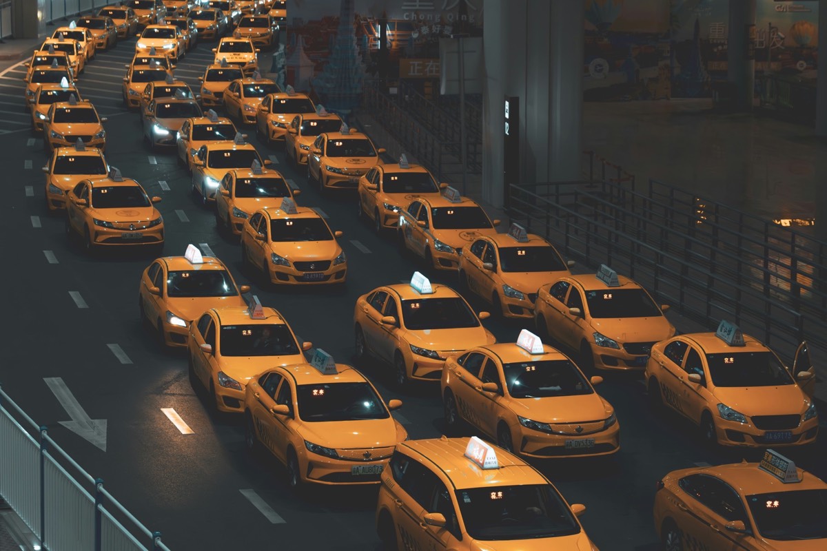 Fleet of yellow taxis queued in rows at night beneath a covered terminal in Chongqing.
