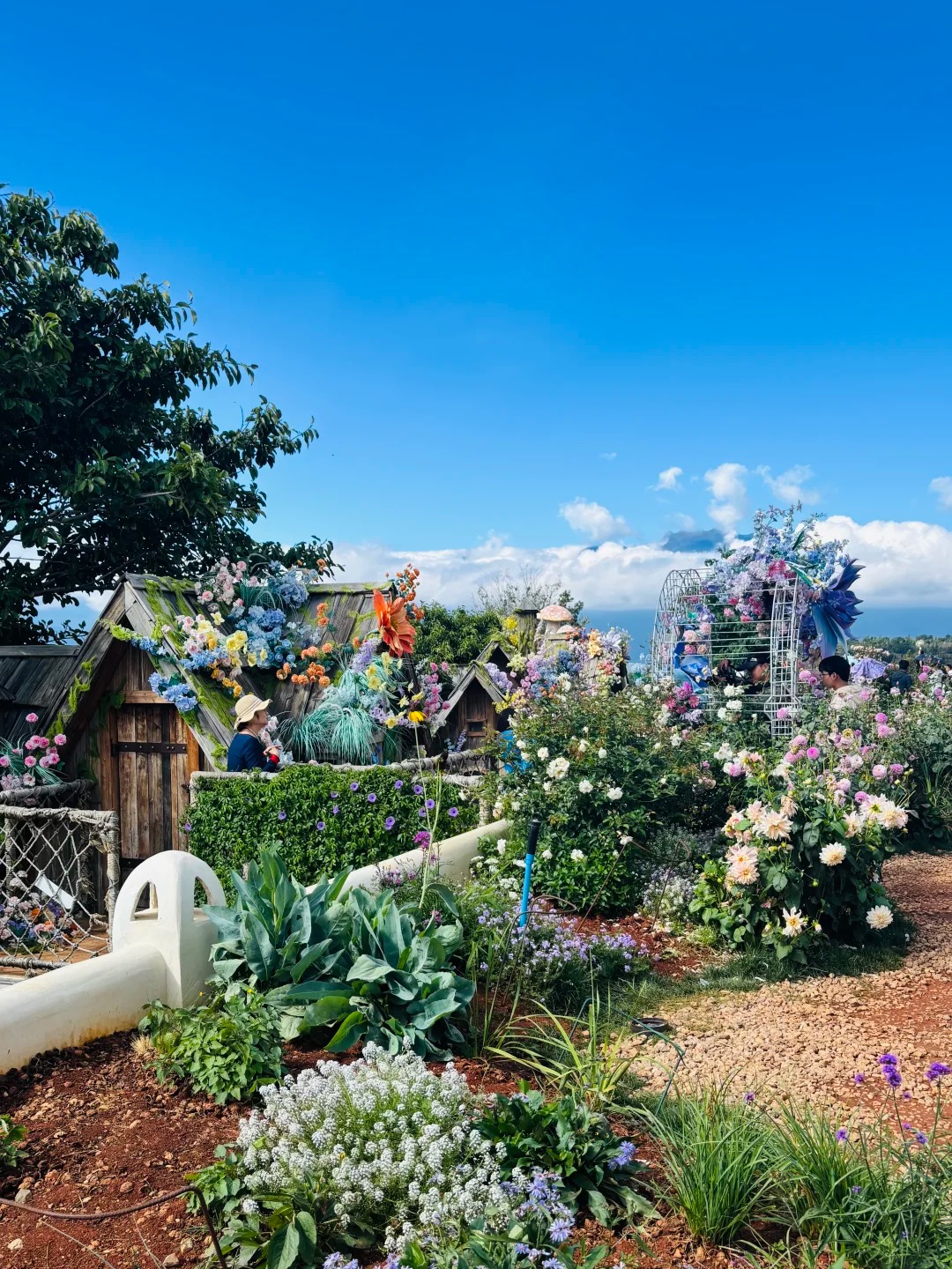 Storybook cottages and flower beds under a blue sky at Fairy Garden, Dali