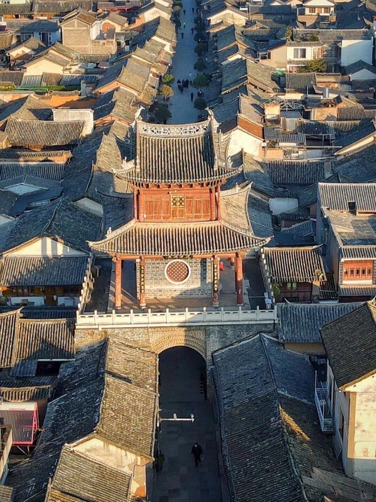 Aerial view of Weishan Ancient Town's tiered gate tower rising above rows of grey-tiled traditional rooftops.
