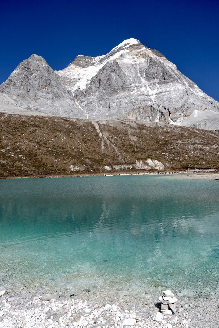 Turquoise milk lake beneath a snow peak on a clear day in Daocheng Yading's inner valley