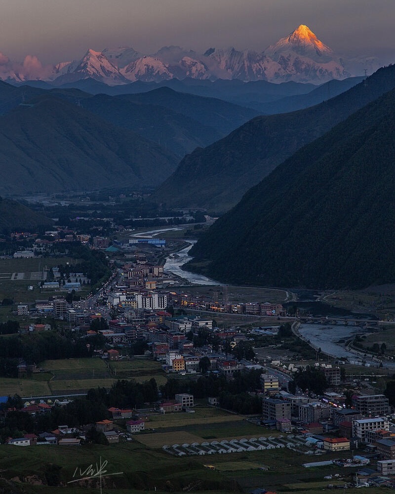 Mt Gongga catches pink alpenglow above Xinduqiao's grasslands at dawn
