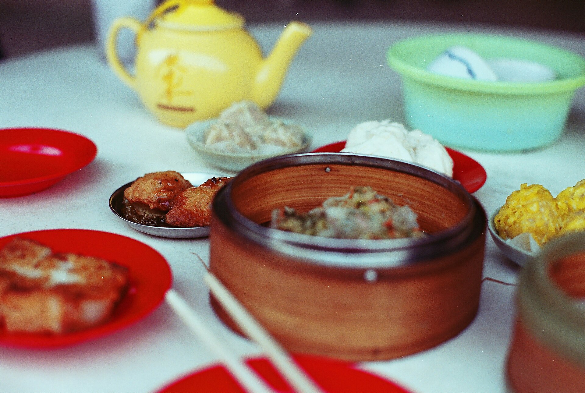A Cantonese yum cha table — bamboo steamers, small fried plates and a yellow teapot, the dim sum morning ritual of Guangzhou