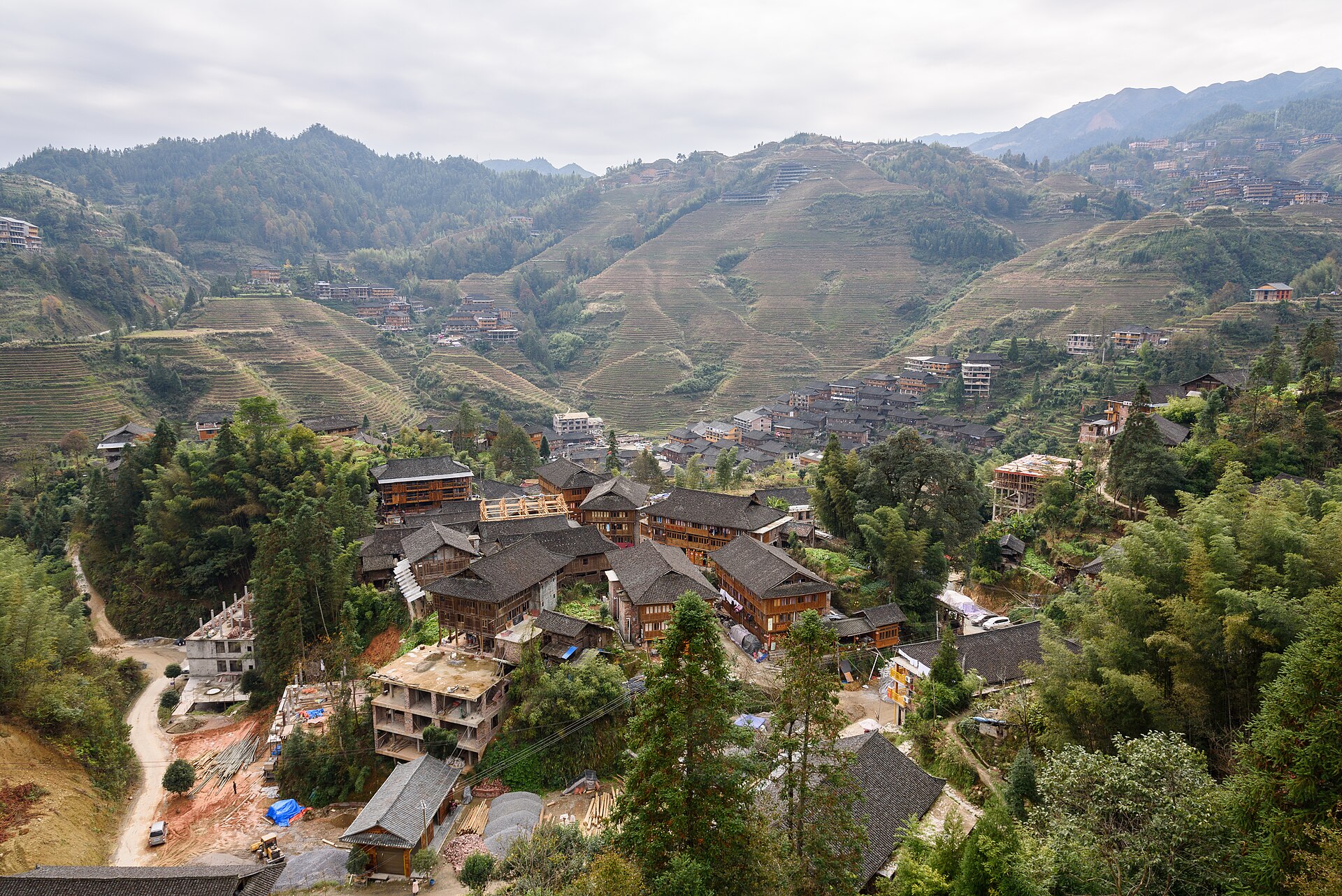 An aerial view over a cluster of grey-timber Zhuang houses ringed by the Longji terraces (龙脊梯田), Guilin