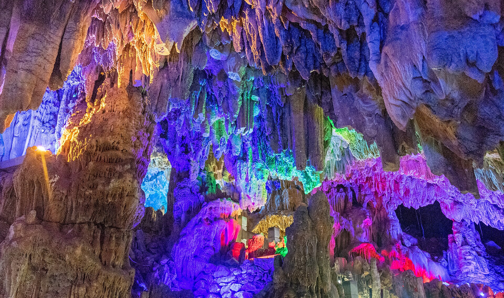 The multicoloured floodlit caverns of Reed Flute Cave (芦笛岩), stalactites glowing purple, blue and green, Guilin