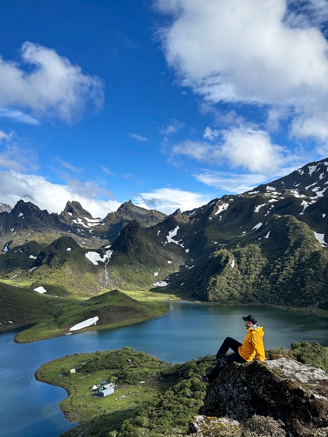 A hiker rests above Black Sea — the alpine tarn at 4,100 m on the slopes of Haba Snow Mountain in northwest Yunnan, hero image for the Black Sea trek by Boutique China