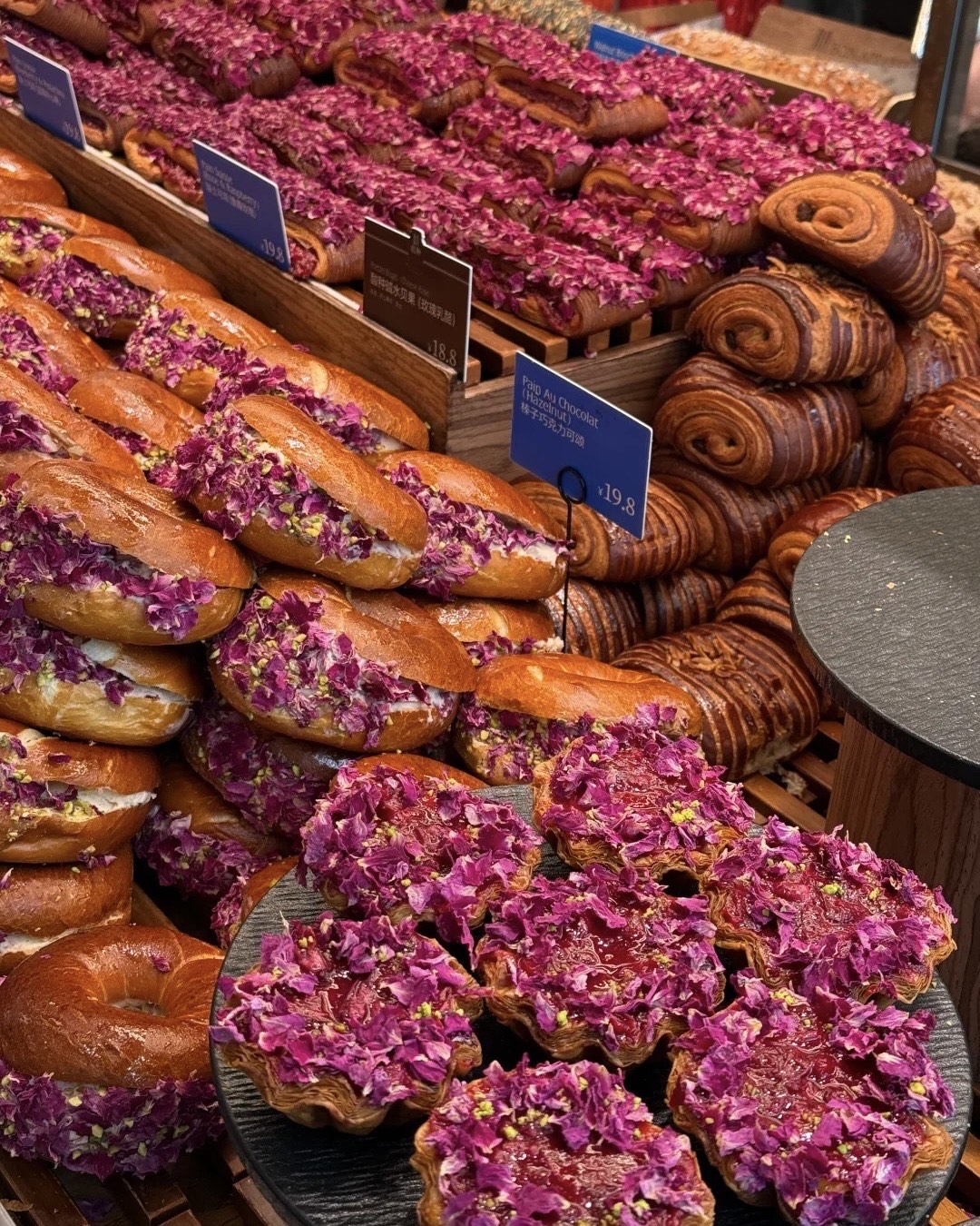 Bakery counter in Kunming piled with rose-petal-topped brioche buns, flaky pastries and croissants with price tags.