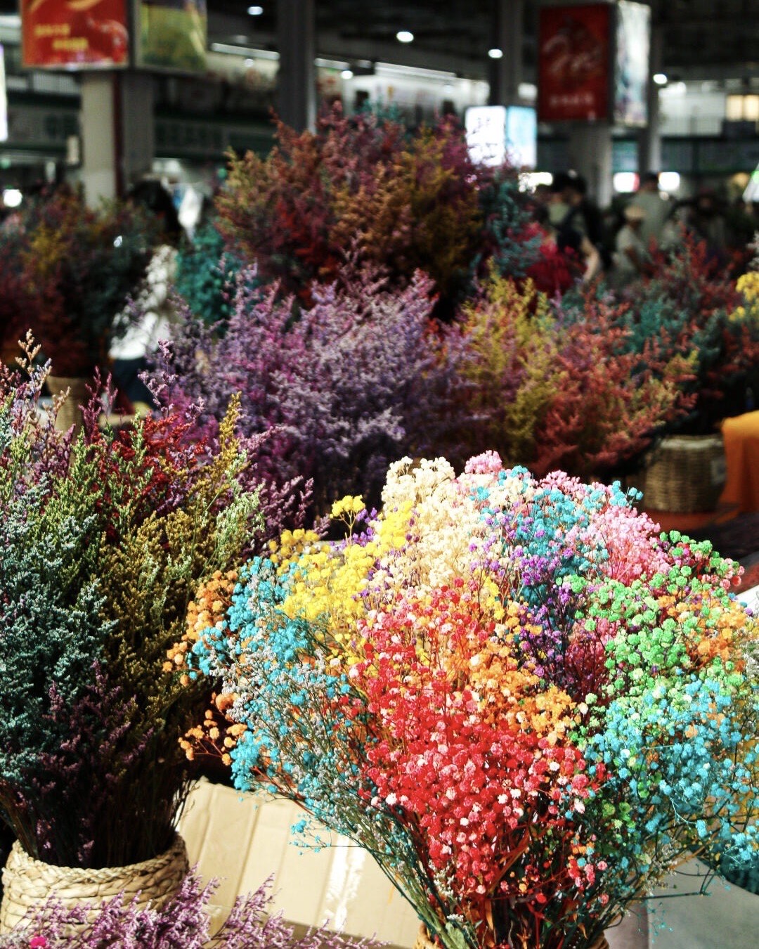 Buckets of brightly dyed dried baby's-breath and preserved flowers fill a stall at a Kunming flower market.