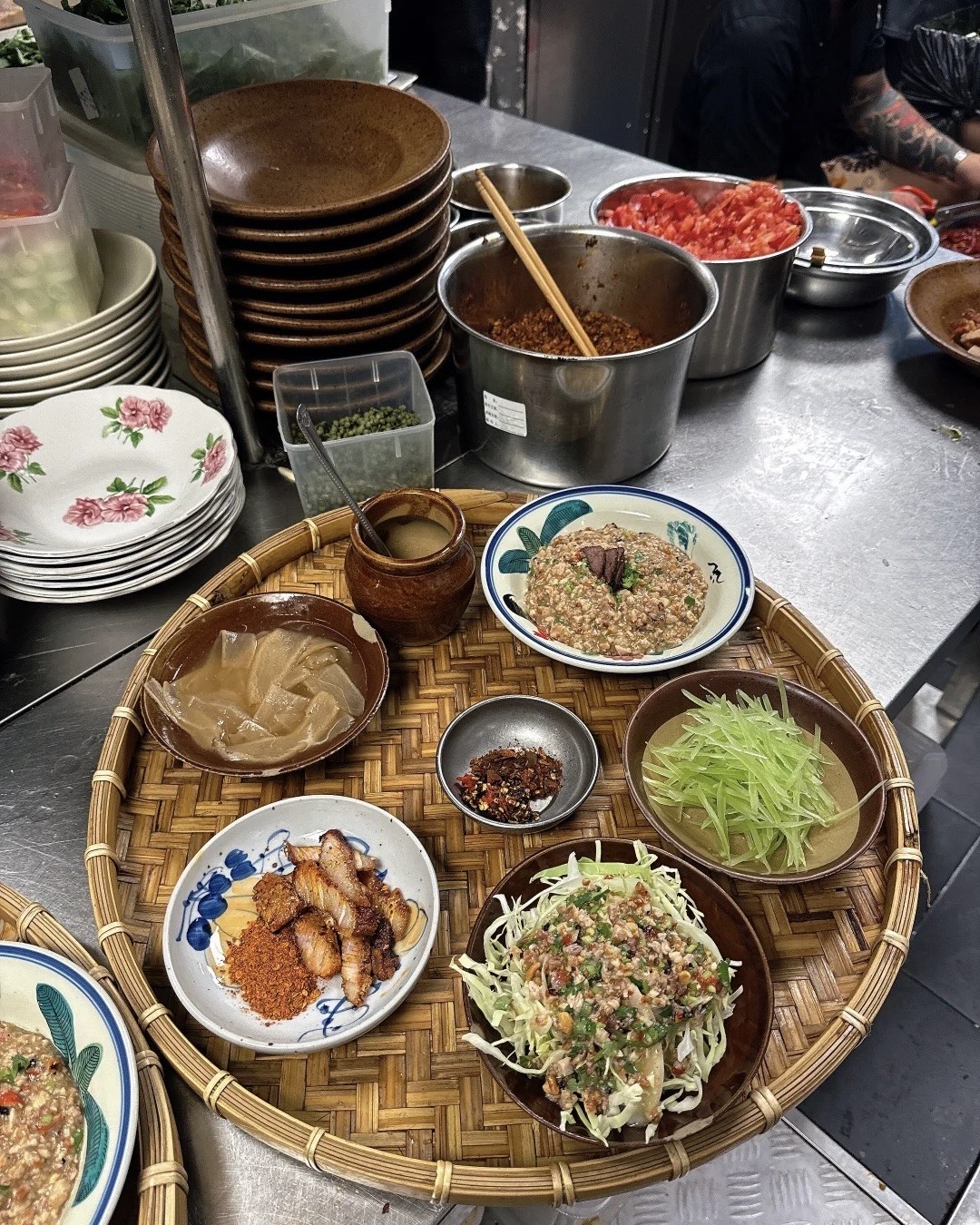 Bamboo tray of Yunnan dishes with cured pork, shredded vegetables, chilli and rice porridge at a Kunming eatery
