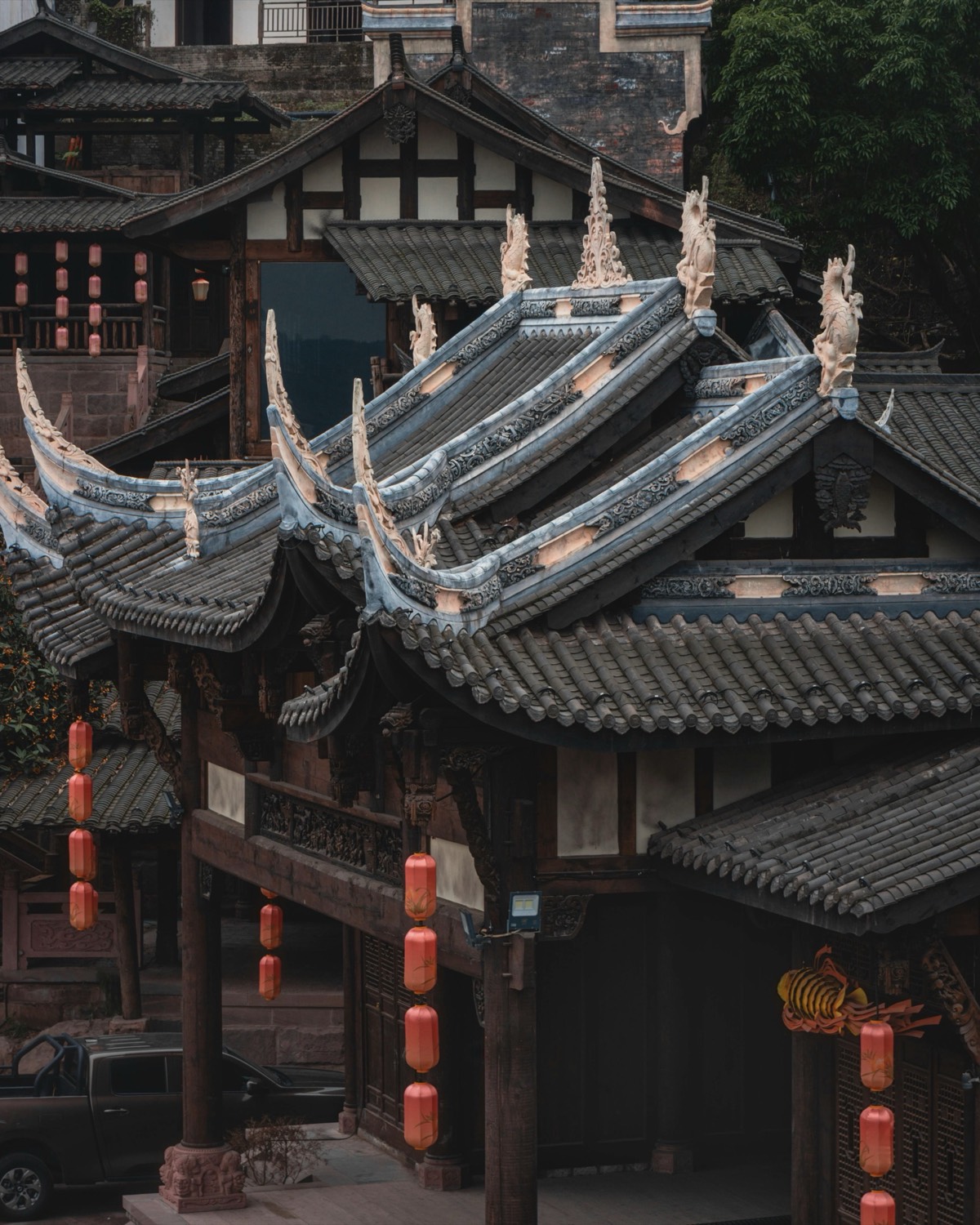 Ornately carved upturned tiled roofs and hanging red lanterns of traditional wooden buildings in Lijiang Old Town.