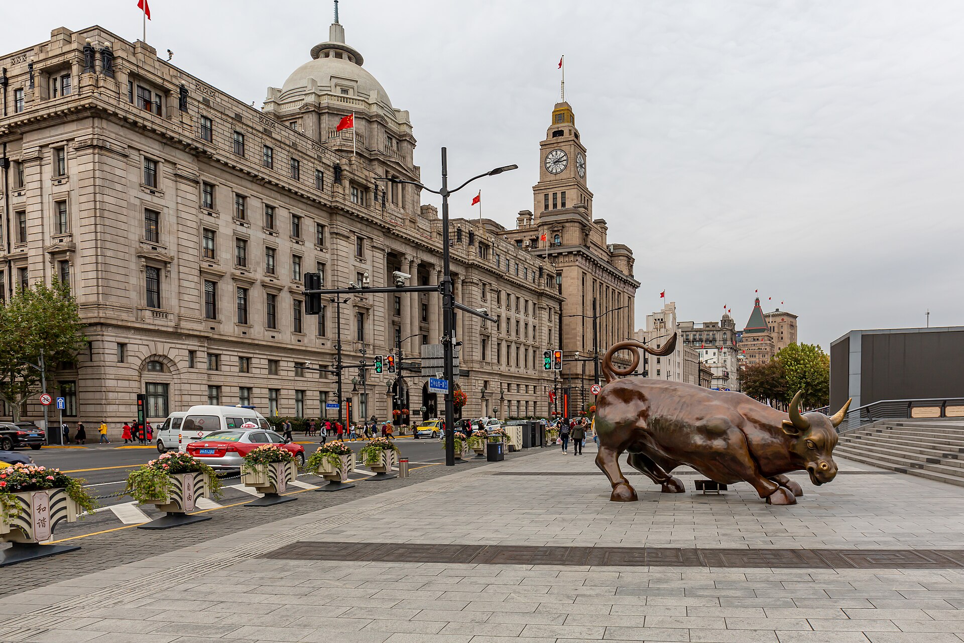 The Bund at street level — the domed former HSBC building and the Customs House clock tower along Shanghai's colonial banking row, the Bund Bull in the foreground