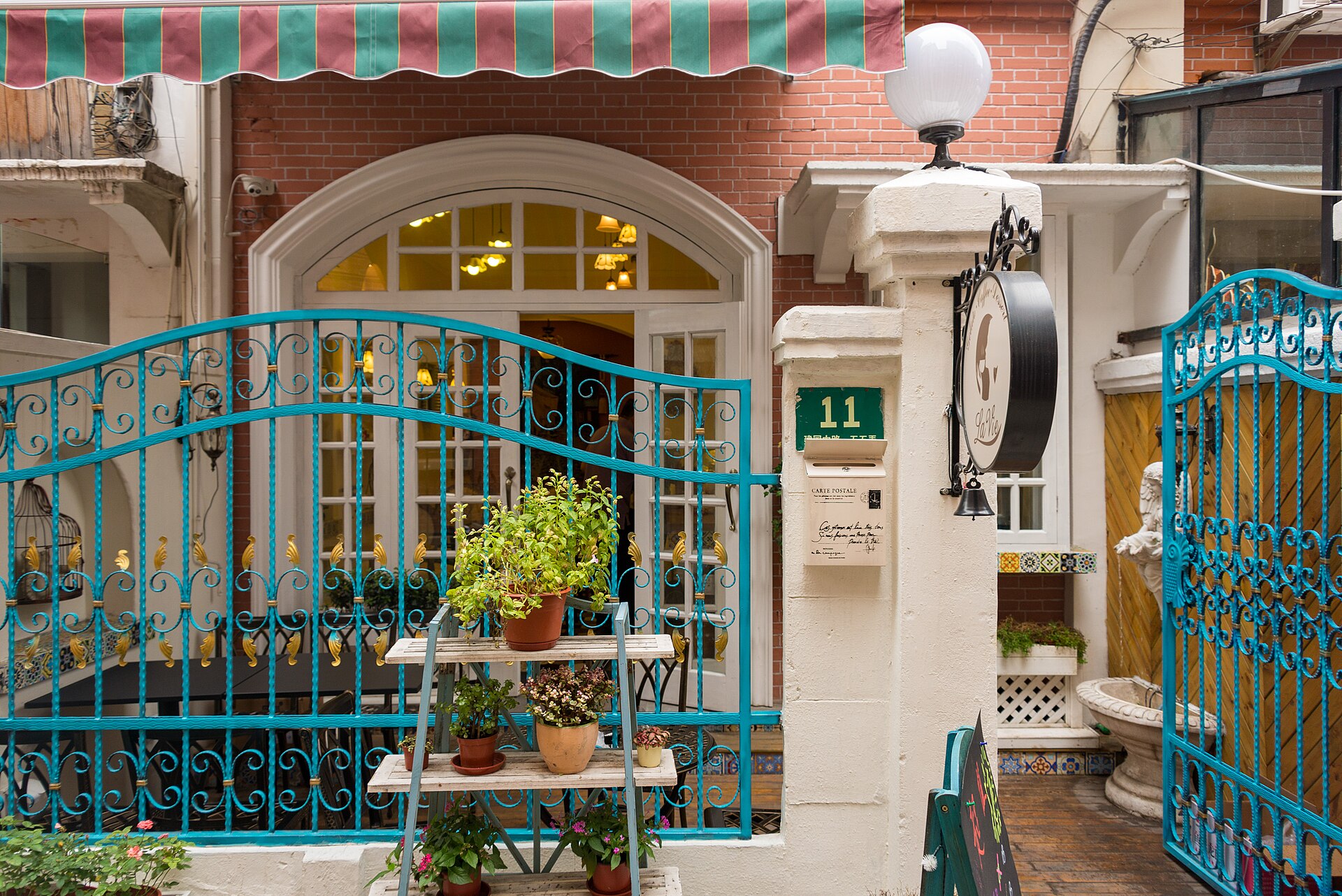 A shikumen (石库门) lane corner in Tianzifang — red brick, an arched doorway and a blue wrought-iron gate, Shanghai's native lane-house architecture