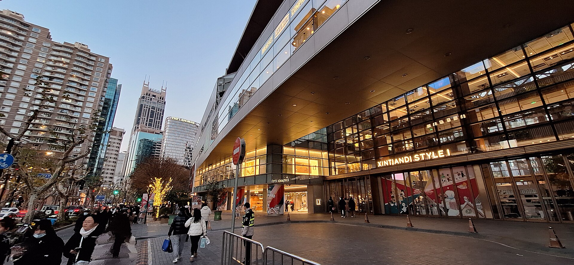 The glass-and-steel Xintiandi (新天地) complex glowing at dusk amid the restored shikumen lanes of Shanghai