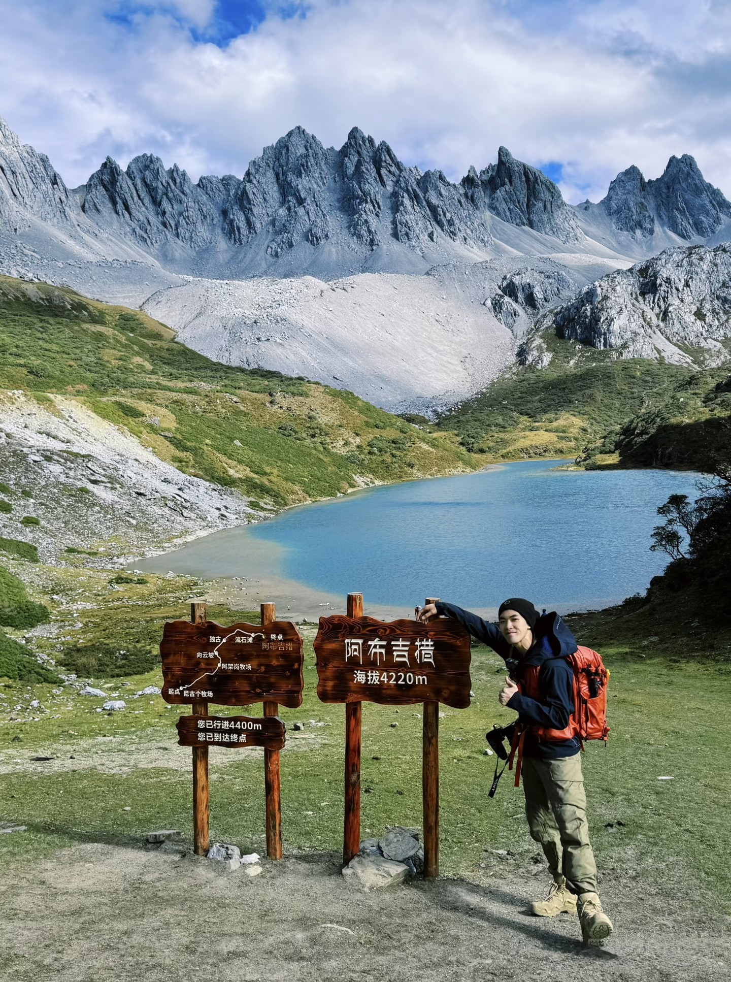 Hiker at the Abujicuo summit sign at 4,220 m above sea level — northwest Yunnan