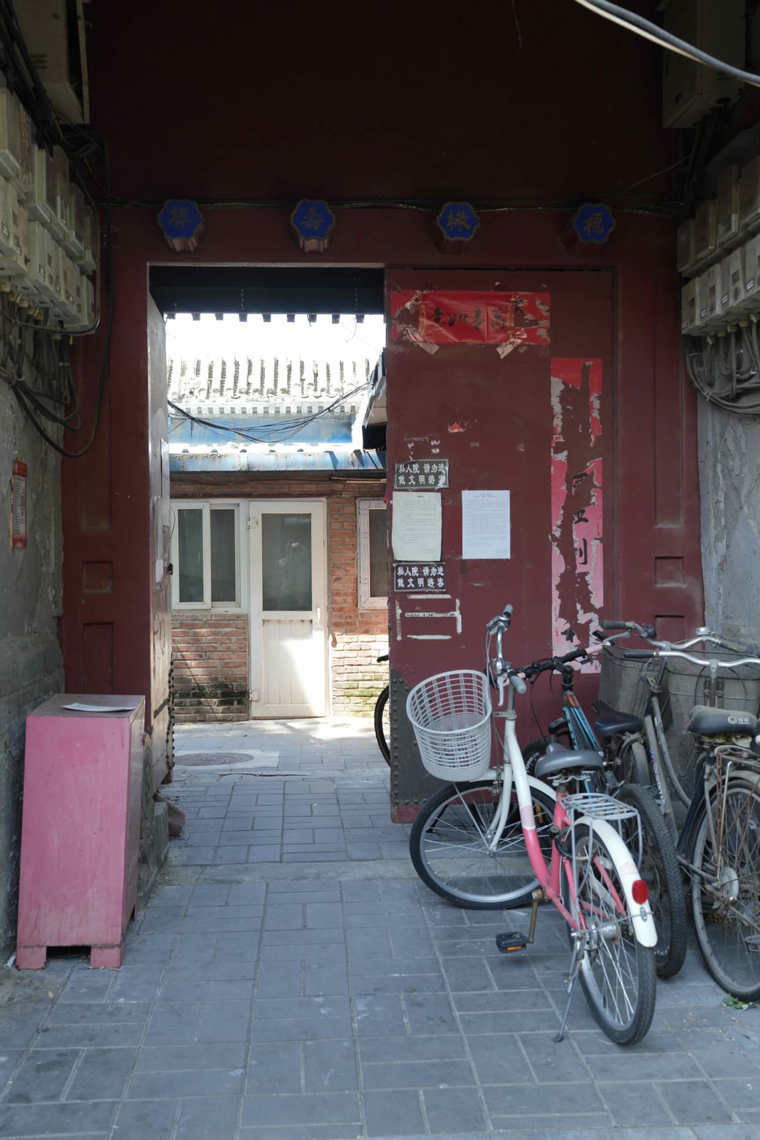 Bicycles parked at a red courtyard gateway in a Beijing hutong — Classic China & Yunnan tour