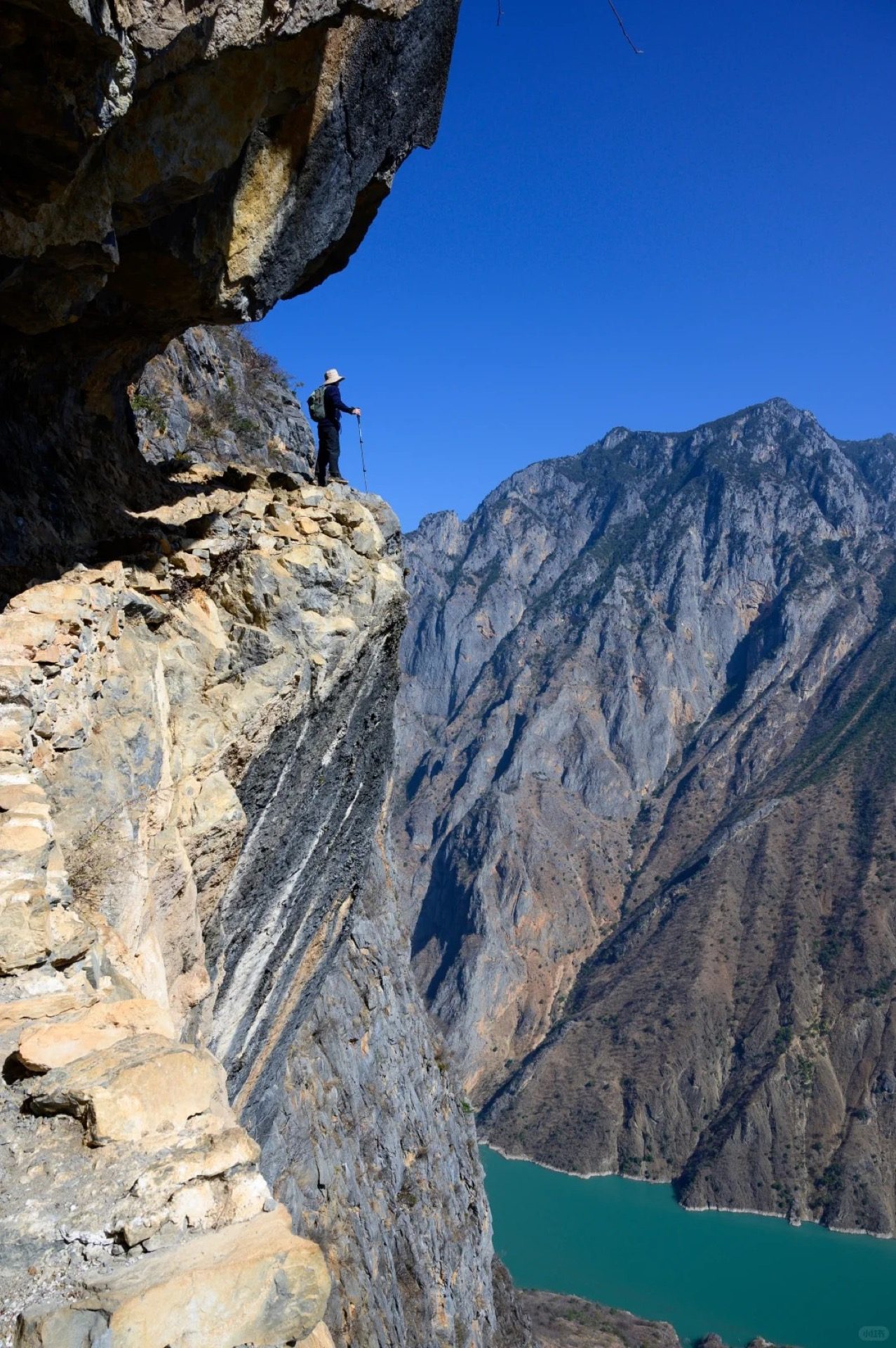 Baoshan Stone City Naxi village pressed against the cliff face above the Jinsha River canyon — the geological drama of the Naxi highlands