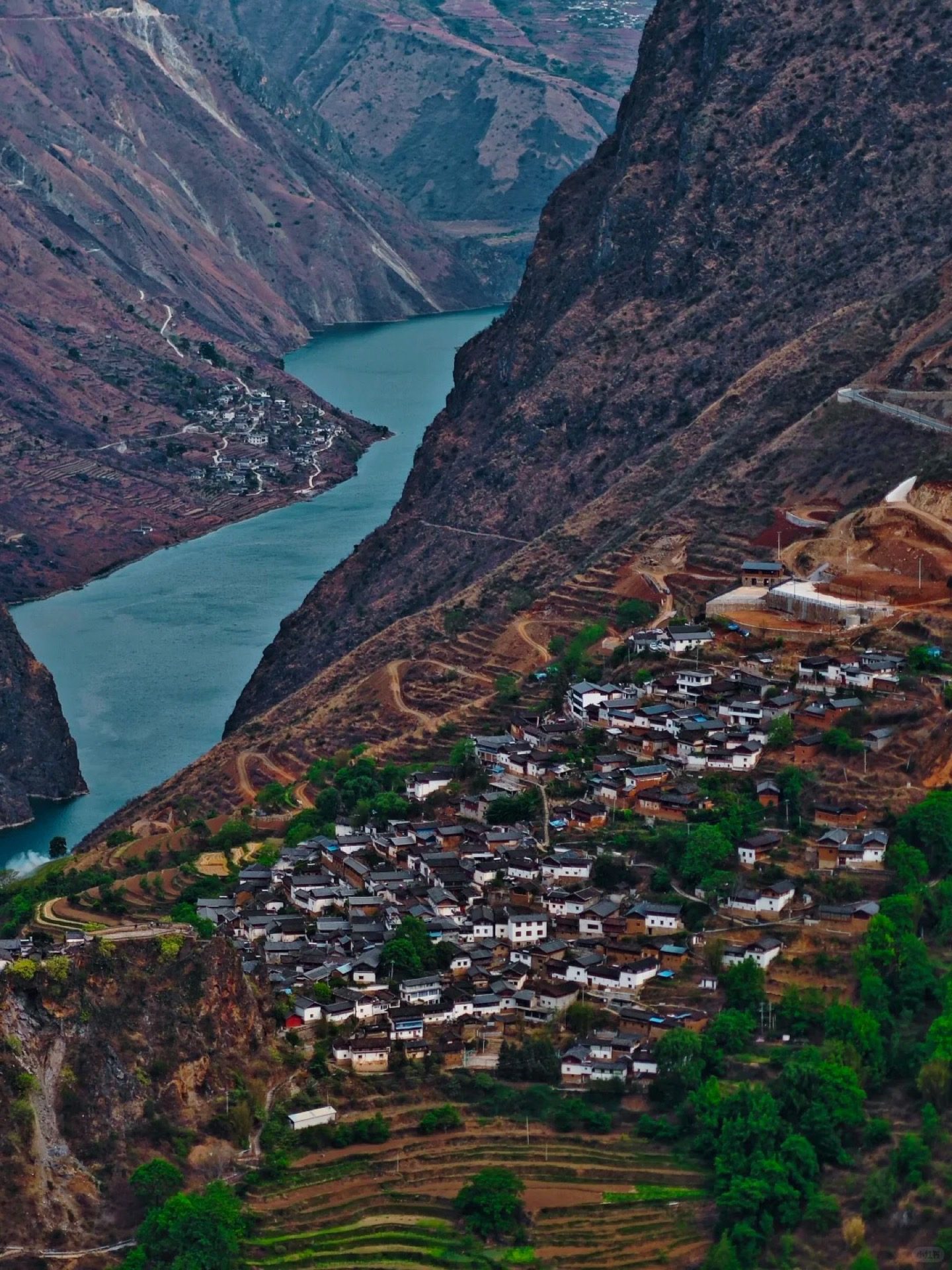 Aerial view of Baoshan Stone City — a Naxi heritage village perched on a cliff above the Jinsha River, glimpsed on the slow return