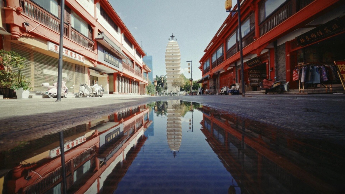 Kunming's East and West Pagodas reflected in a rain puddle on a quiet city street — China's Last Frontier loop