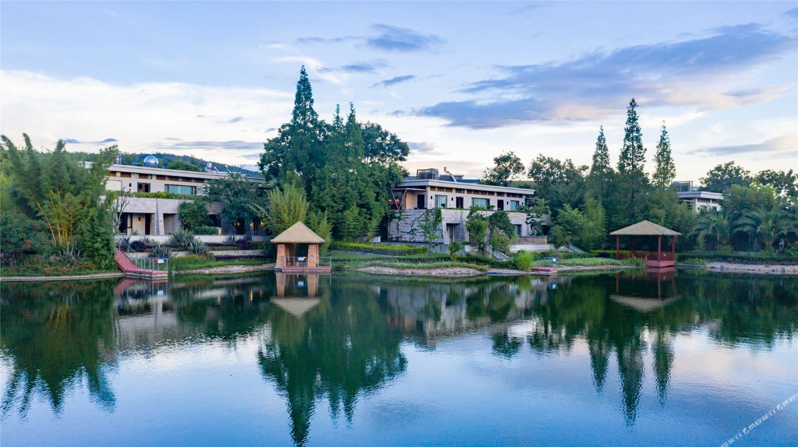 Wanda Vista Yuxi Fuxian Lake (抚仙湖万达文华酒店) — pavilions and villas reflected in the resort's lagoon at dusk