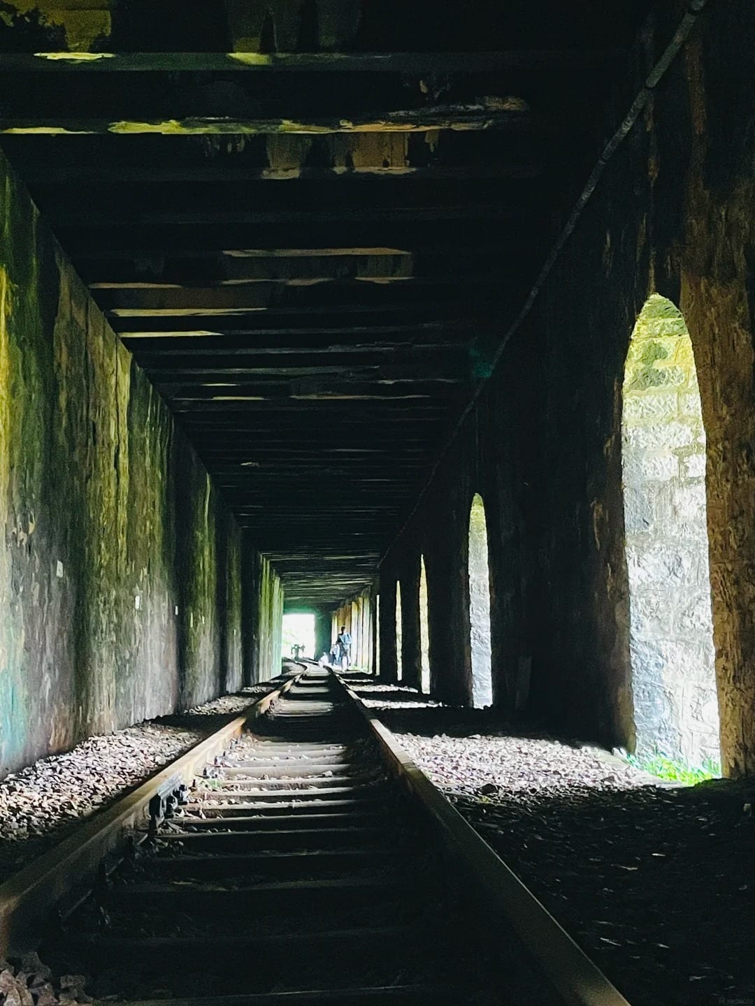 An arched gallery on the Yunnan–Vietnam Railway, daylight falling through its open arches onto the metre-gauge track