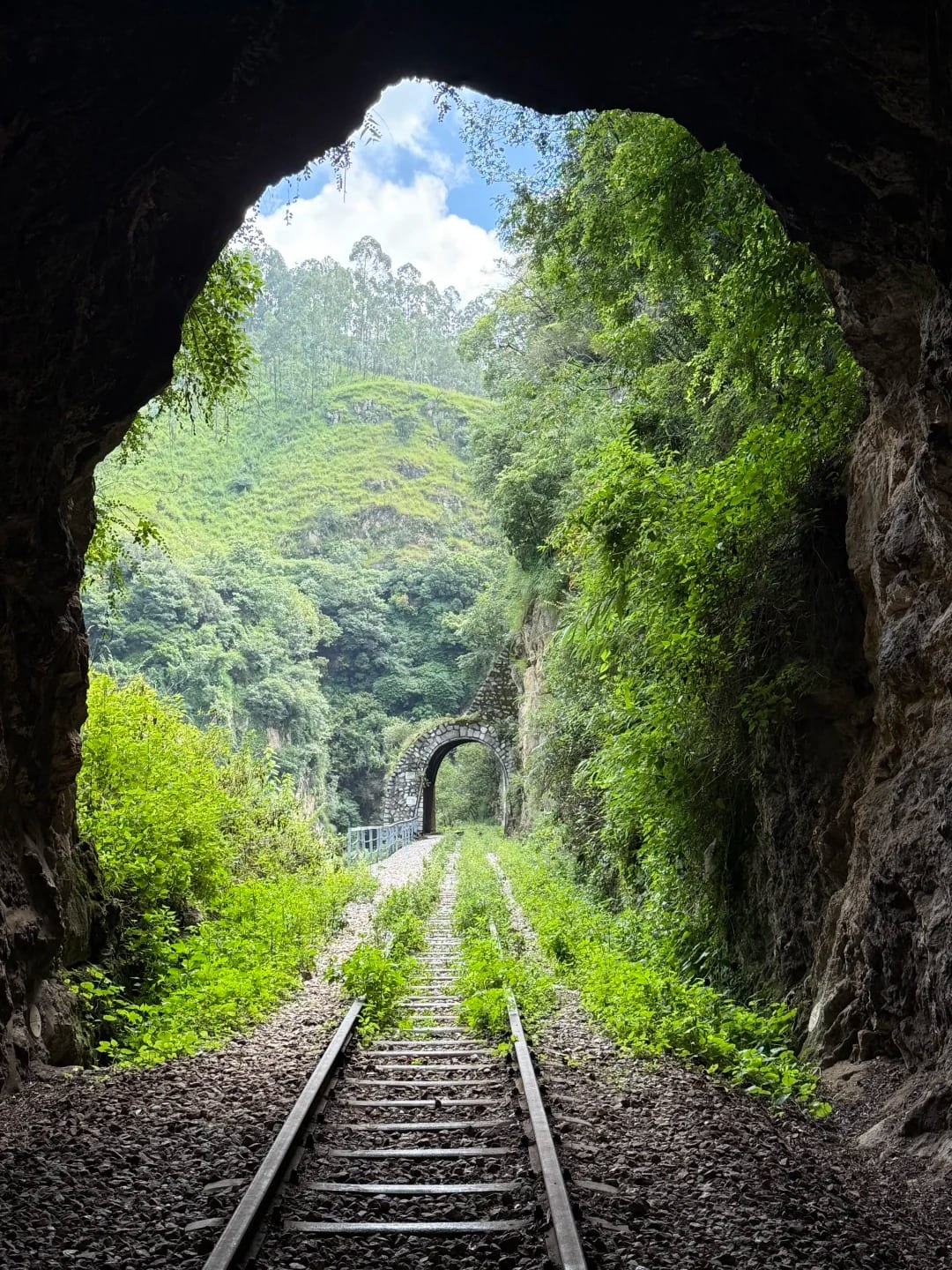 Looking out of a tunnel on the Yunnan–Vietnam Railway (滇越铁路) towards the next one, the metre-gauge track running between green cuttings near Yiliang