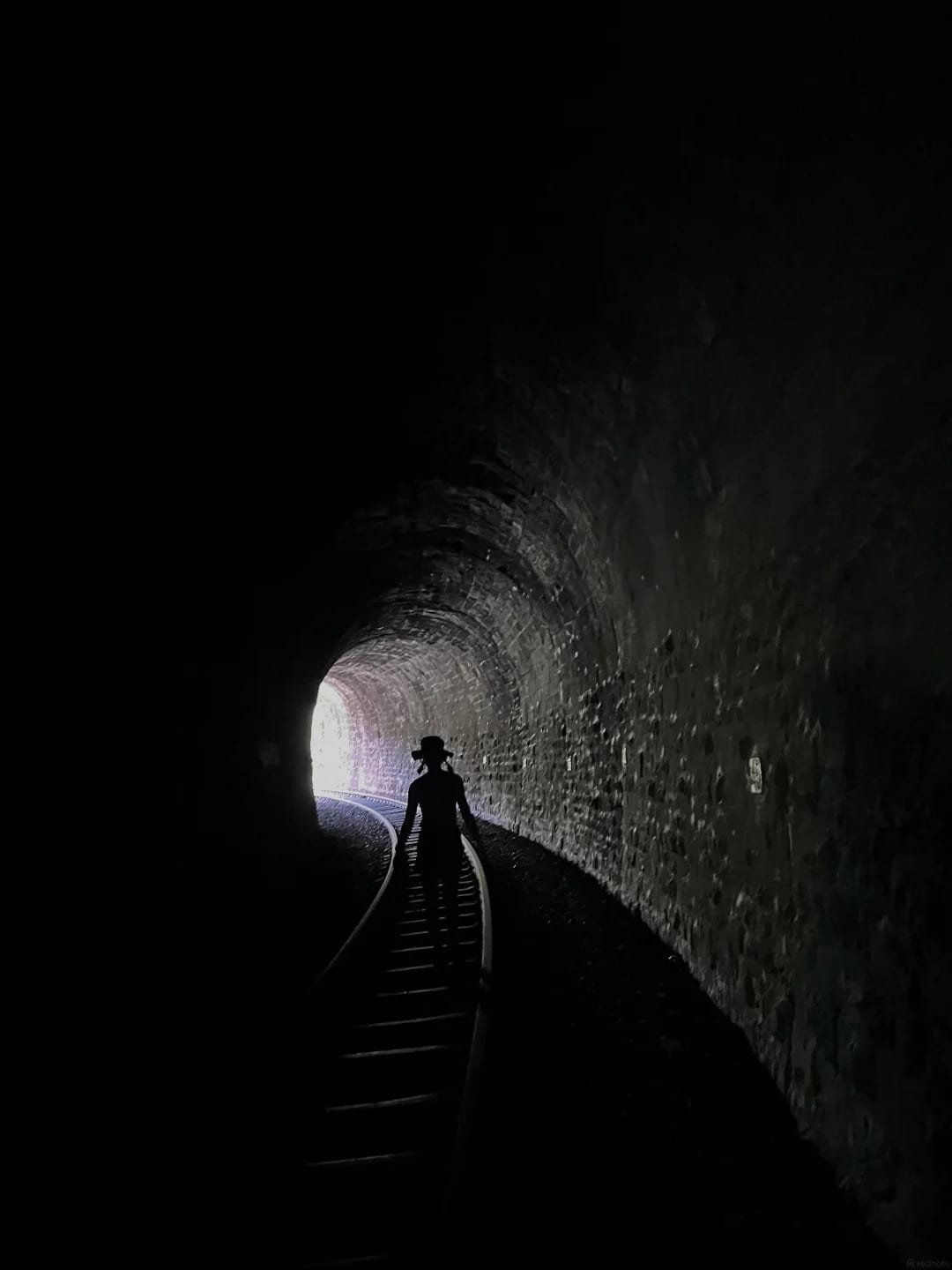 A walker silhouetted in one of the longer tunnels on the Yunnan–Vietnam Railway, heading for the light at the far end