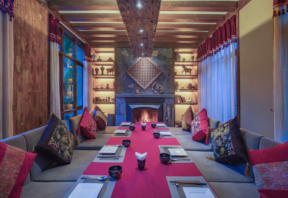 Arro Khampa — private dining alcove set with Tibetan brocade cushions and a long table by the fireside