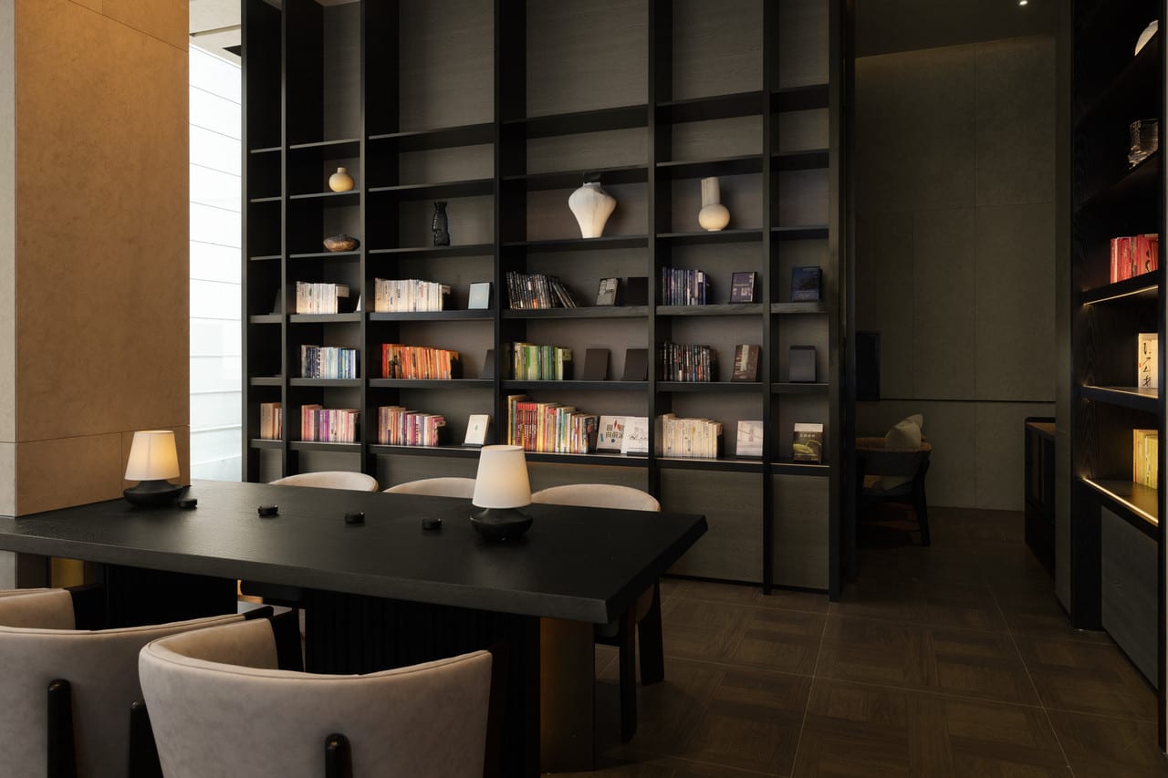 Atour Hotel, Zhangjiajie Forest Park Gate — the library lounge, a long reading table before tall shelves of books and ceramics