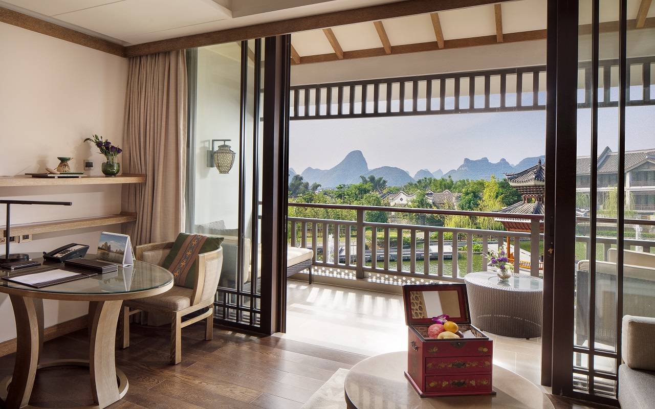 Banyan Tree Yangshuo — suite with balcony over the lagoon gardens, karst peaks on the horizon