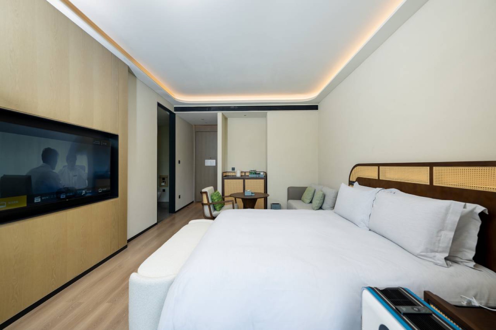 Bilangwan Hot-Spring Resort — a contemporary guest room with a caned rattan headboard, wood panelling and an inset TV