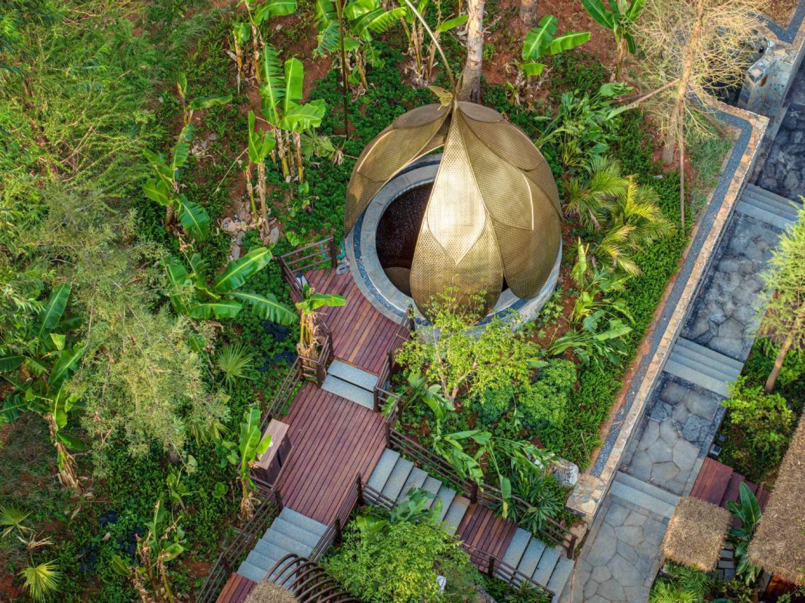 Bilangwan Hot-Spring Resort — a lotus-petal brass-mesh bathing pavilion over a stone thermal pool, set among banana palms and terraced gardens