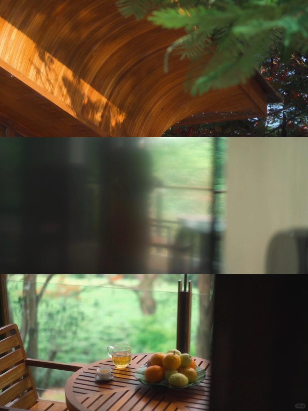 Wooden balcony table with a pot of tea and bowl of fruit beside a window onto green forest.