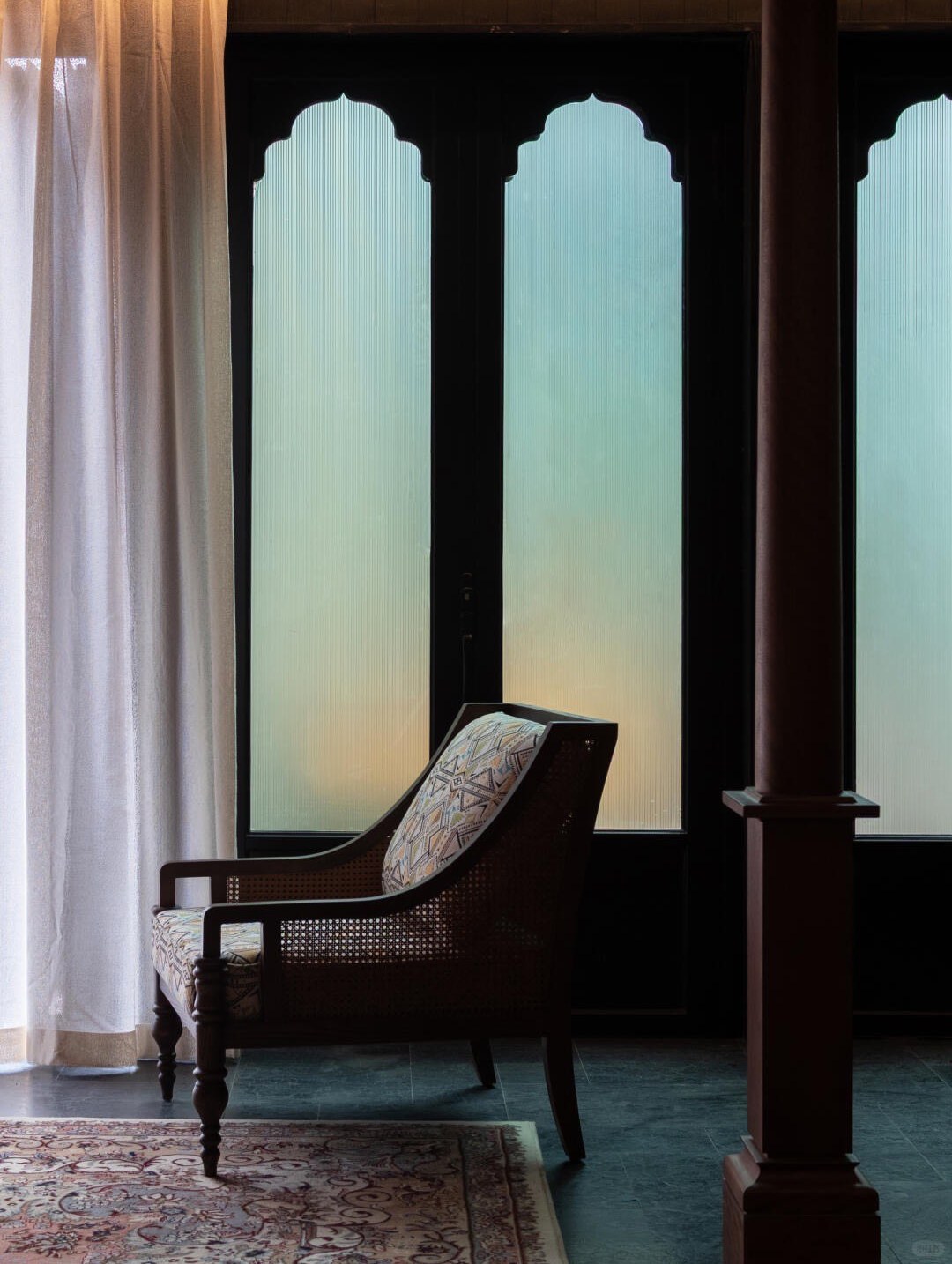 Bore Yading — a rattan armchair before arched frosted windows in a Tibetan-style suite