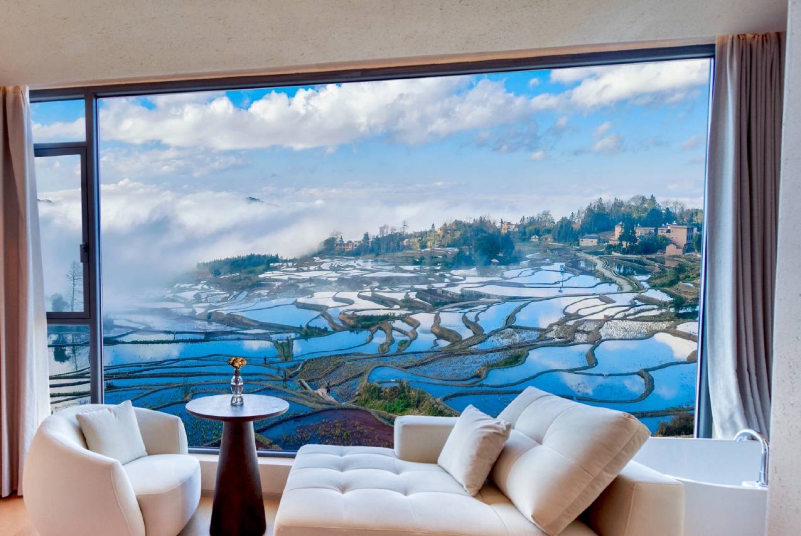 Daotian Lixiang — guest lounge with a floor-to-ceiling window filling the frame with the flooded Yuanyang terraces under blue sky and cloud