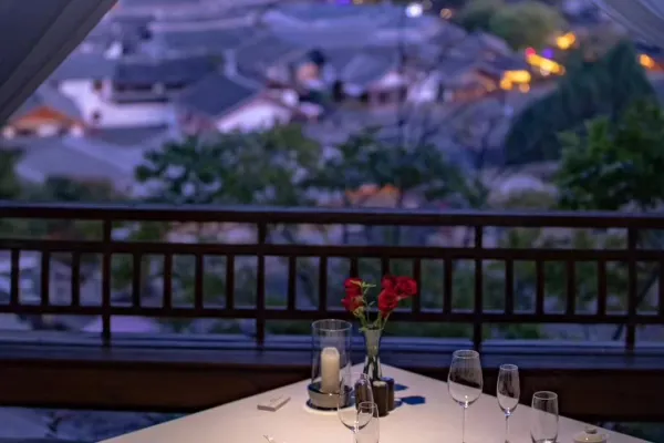 Candlelit balcony table with red roses and wine glasses overlooking a glowing old town at twilight at Dayanaman.