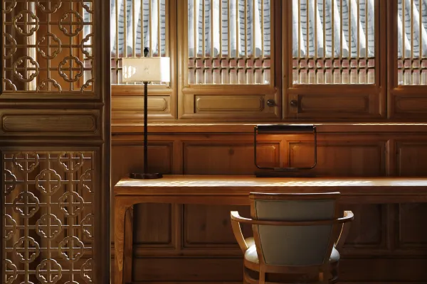 Wooden reading desk and chair beside carved lattice screens and shuttered windows in a timber-panelled room at Dayanaman.