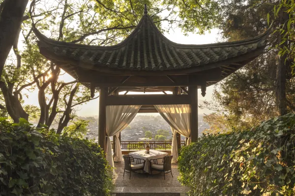 Curved-roof Chinese pavilion set with a private dining table overlooking the rooftops of an old town at Dayanaman.