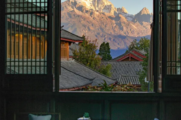 View through an open window across grey-tiled courtyard roofs to a snow-capped mountain at Dayanaman.