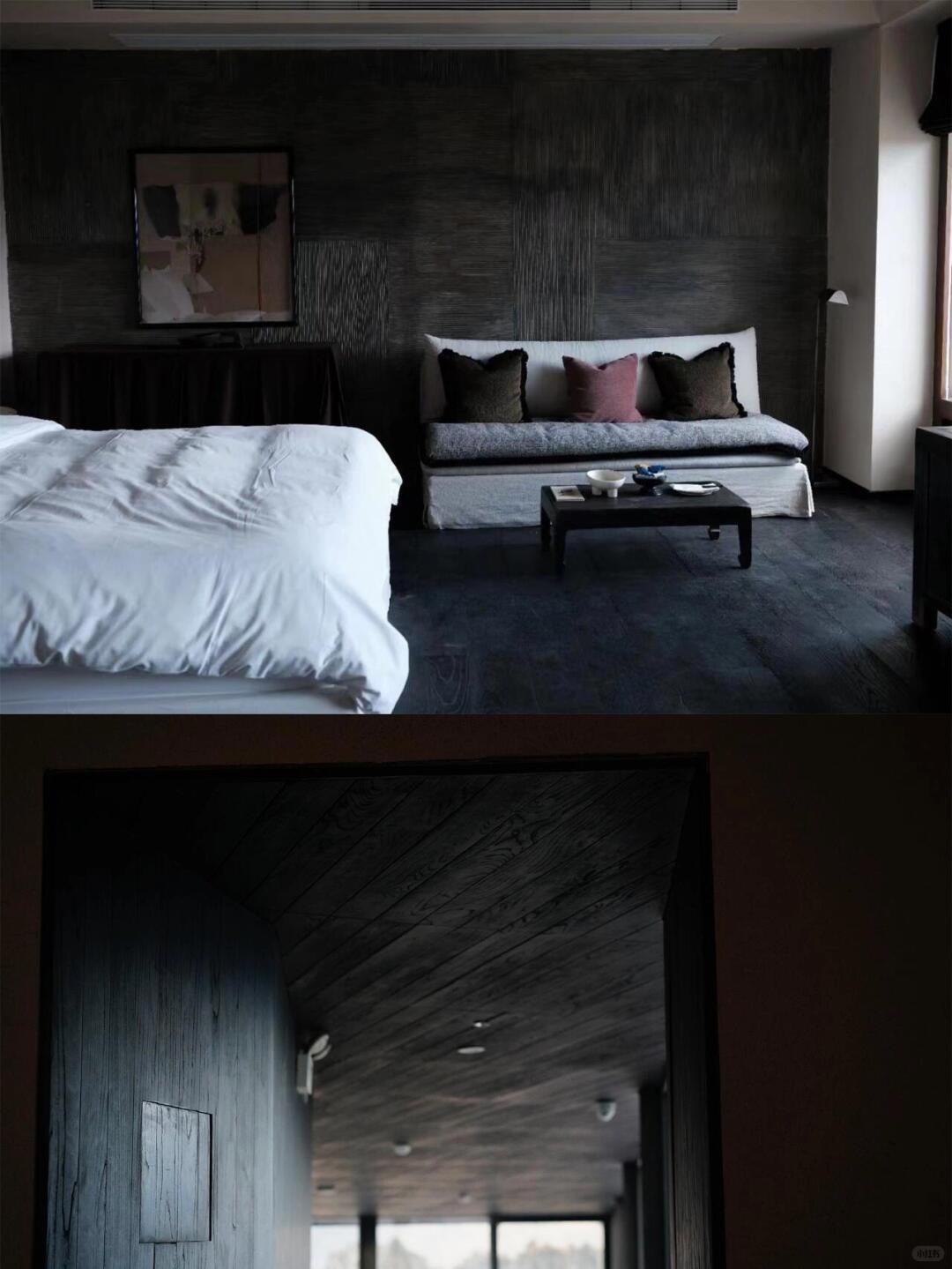 Dim suite with white-linen bed, cushioned daybed and dark timber-lined corridor beyond.